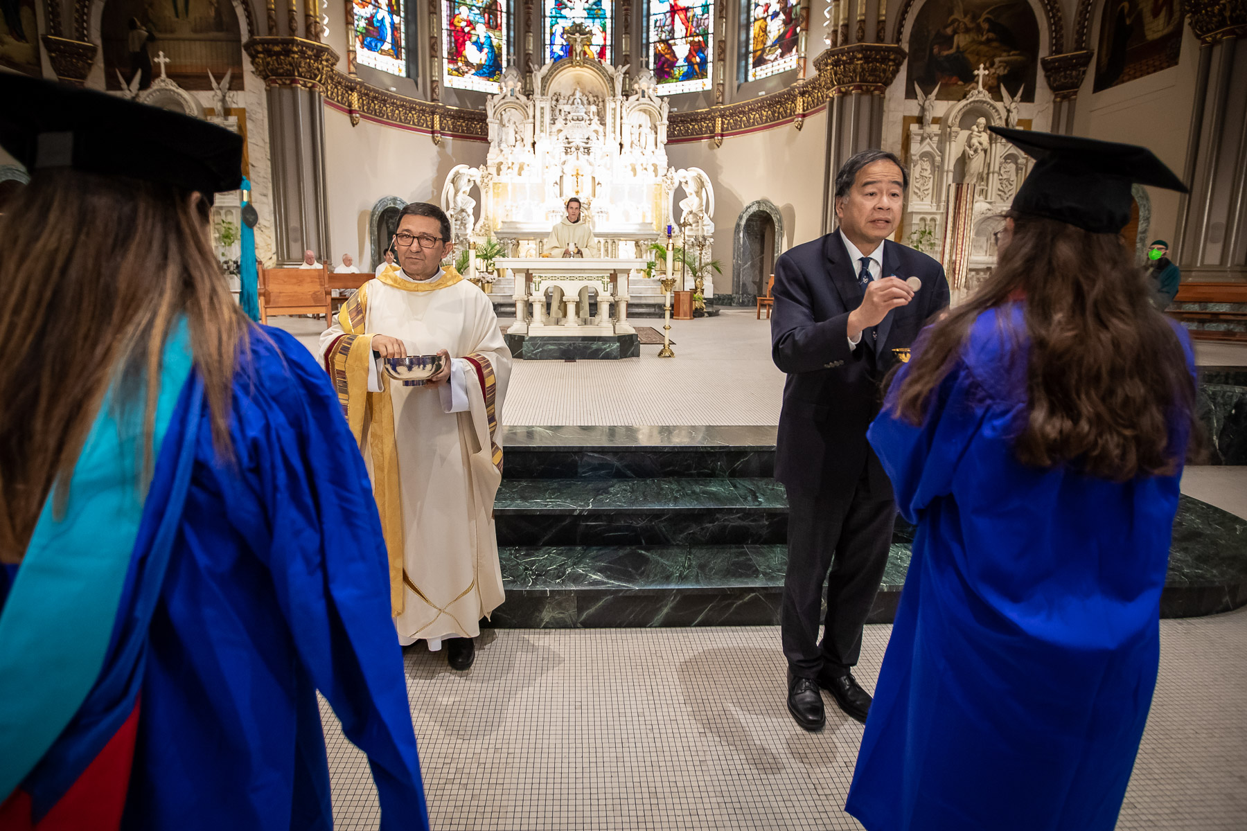 Rev. Guillermo Campuzano, C.M., and Dr. A. Gabriel Esteban, president, distribute communion during Baccalaureate Mass.